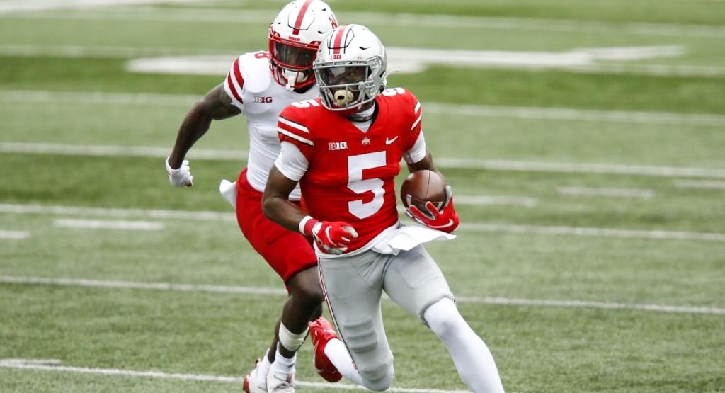Ohio State wide receiver Garrett Wilson runs with ball in his hands against Nebraska. Wilson is wearing the red jeresey adorning a white number 5.