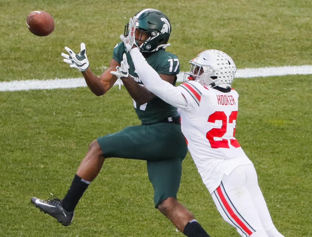 Ohio State Safety Marcus Hooker knocks away a pass intended for a Michigan State receiver. Booker is wearing a white jersey adorning a red 23.