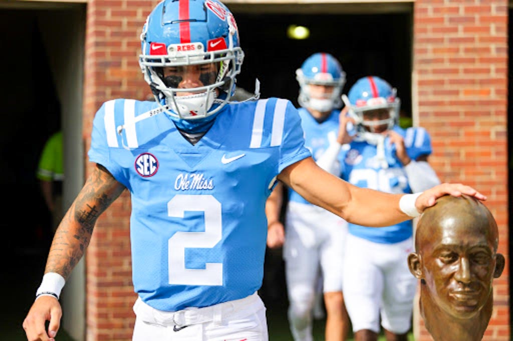 Ole Miss QB Matt Coral touches a bronze head on his way to the field.